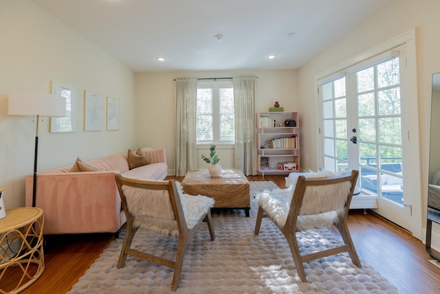 living area with healthy amount of natural light, wood finished floors, recessed lighting, and french doors