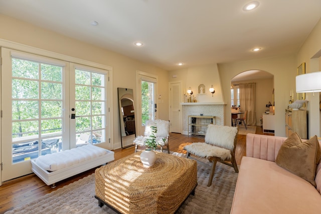 living area with arched walkways, wood finished floors, recessed lighting, and a fireplace with flush hearth
