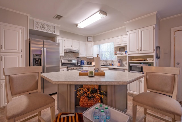 4203 Glenda Ln, Benton, AR 72019 - kitchen with stainless steel appliances, under cabinet range hood, light countertops, decorative backsplash, and ornamental molding