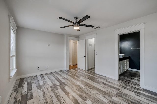 1005 S German Ln, Conway, AR 72034 - unfurnished bedroom with wood finished floors, ensuite bath, and ceiling fan