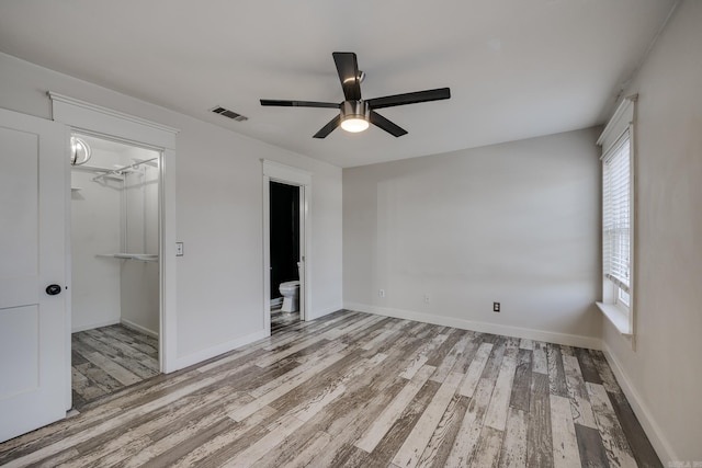 1005 S German Ln, Conway, AR 72034 - unfurnished bedroom featuring wood finished floors, a spacious closet, a closet, and ceiling fan