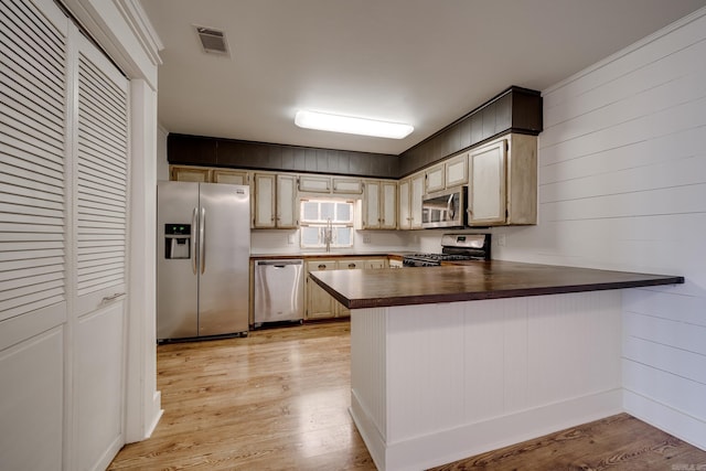1005 S German Ln, Conway, AR 72034 - kitchen featuring stainless steel appliances, a peninsula, light wood-style flooring, butcher block countertops, and wooden walls