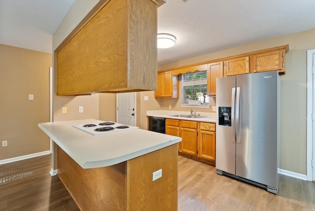 1410 Pyramid Dr, Conway, AR 72032 - kitchen featuring stainless steel fridge with ice dispenser, cooktop, light countertops, light wood finished floors, and a peninsula