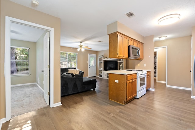 1410 Pyramid Dr, Conway, AR 72032 - kitchen featuring white range with electric cooktop, stainless steel microwave, wood finished floors, light countertops, and healthy amount of natural light