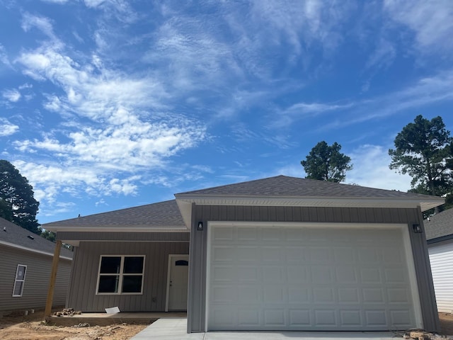 ranch-style house with roof with shingles, a garage, board and batten siding, concrete driveway, and covered porch