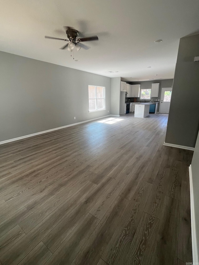 unfurnished living room with dark wood-style flooring and a ceiling fan
