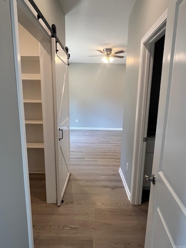 hall with a barn door and wood finished floors