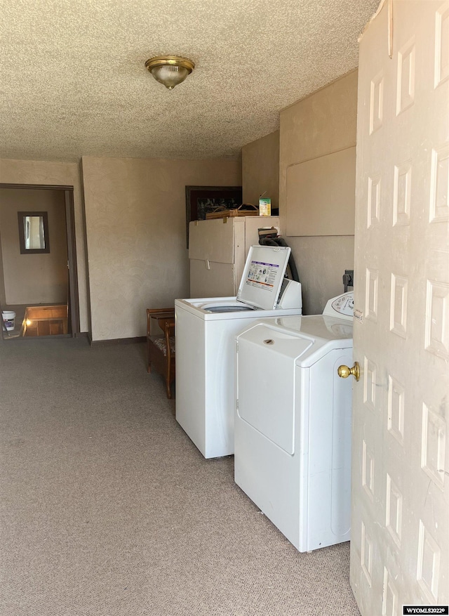 laundry area featuring light carpet, a textured ceiling, and washer and clothes dryer