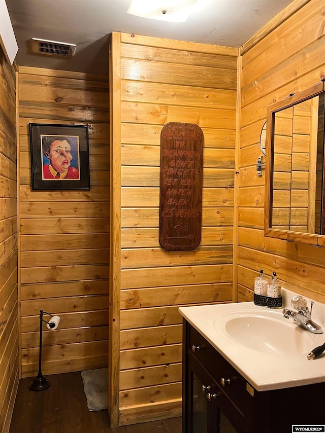 bathroom featuring hardwood / wood-style flooring, wood walls, and vanity