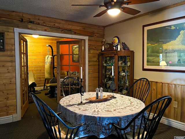 carpeted dining room with ceiling fan, a textured ceiling, and wooden walls