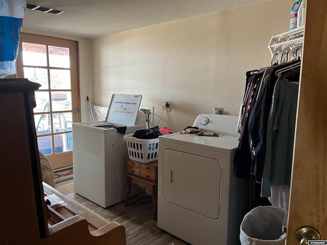 laundry area featuring washing machine and clothes dryer, washer hookup, a textured ceiling, and wood-type flooring