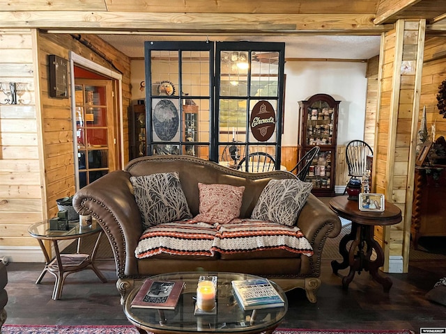 living room with wood walls, dark hardwood / wood-style floors, and beamed ceiling