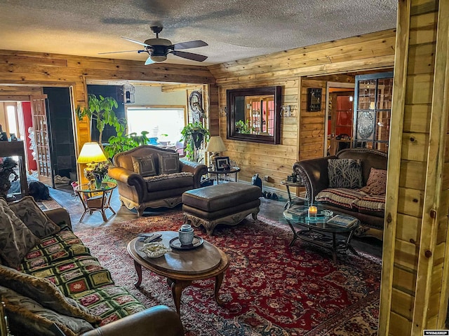 living room with a textured ceiling, wooden walls, and ceiling fan