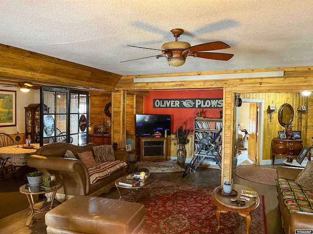 living room with wooden walls, ceiling fan, and a textured ceiling