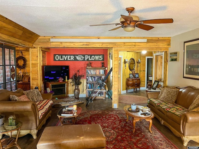 living room featuring wooden walls, ceiling fan, and a textured ceiling