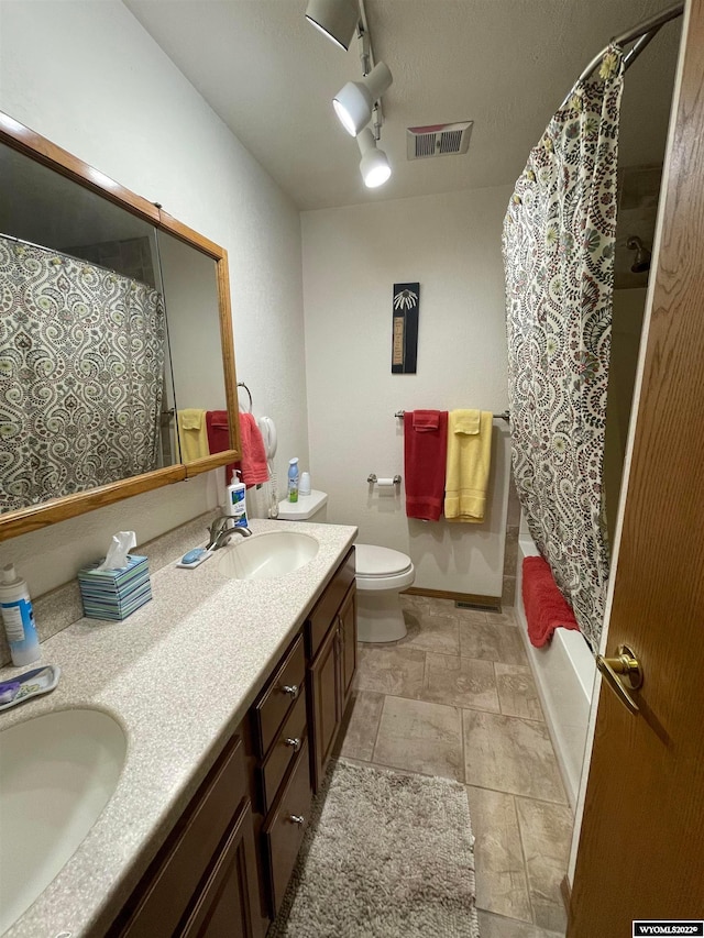 full bathroom featuring toilet, dual vanity, rail lighting, shower / bathtub combination with curtain, and tile floors