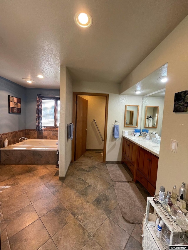 bathroom featuring tiled bath, a textured ceiling, tile flooring, and oversized vanity