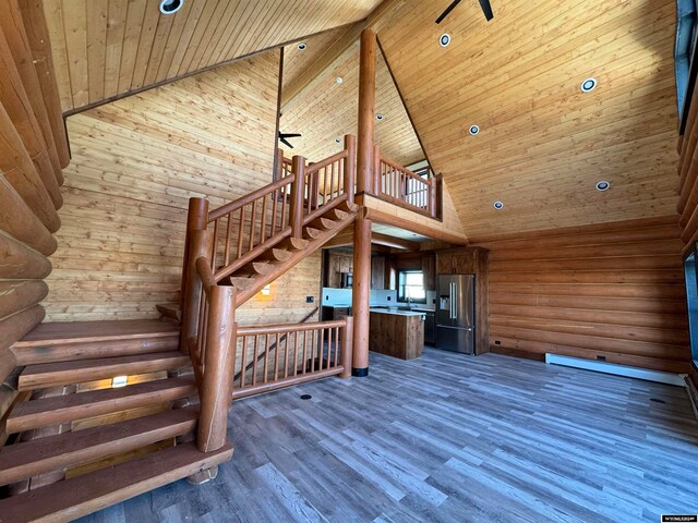 staircase featuring wood-type flooring, high vaulted ceiling, rustic walls, and wood ceiling