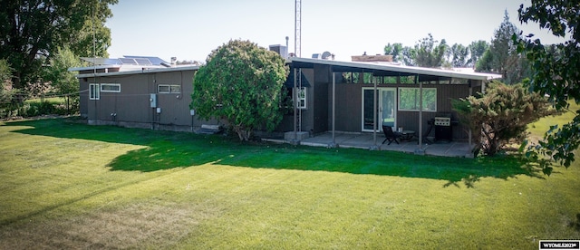 rear view of house featuring solar panels, a patio area, and a yard