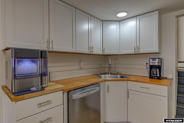 kitchen with wooden counters, white cabinets, stainless steel dishwasher, and sink