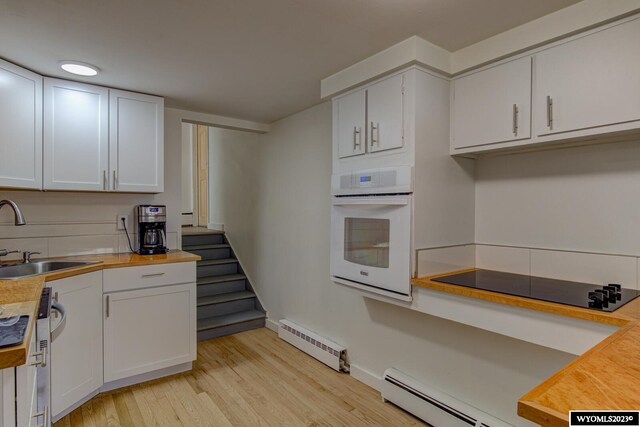 kitchen with white oven, light hardwood / wood-style floors, black electric cooktop, sink, and white cabinets