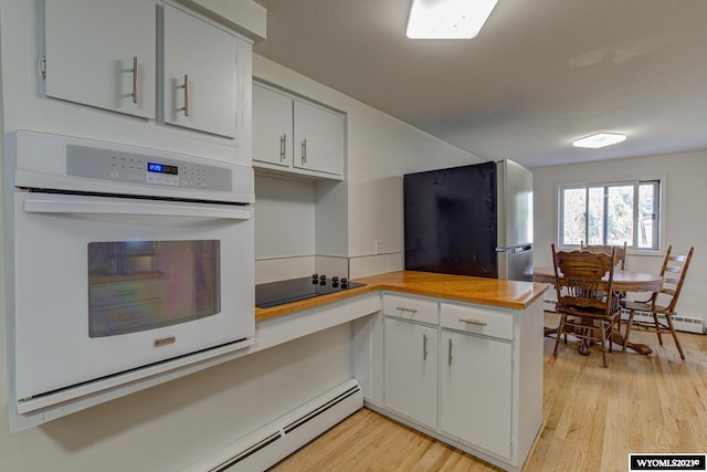 kitchen with fridge, black electric stovetop, light hardwood / wood-style floors, oven, and white cabinets