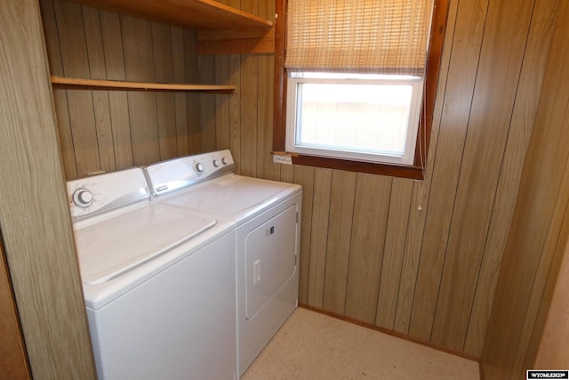 washroom with washing machine and clothes dryer and wood walls