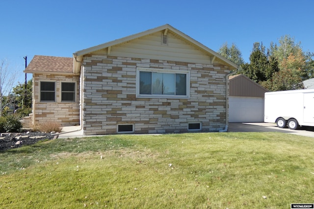 view of property exterior featuring a garage, a yard, and an outbuilding