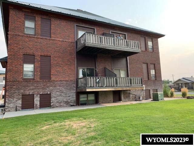 back of house featuring a balcony and a yard