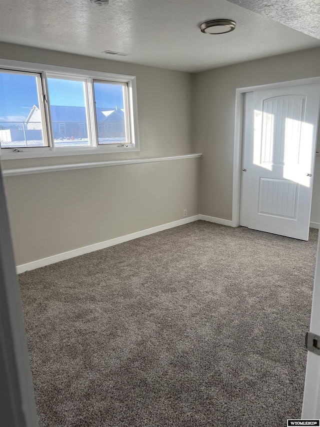 carpeted spare room featuring plenty of natural light and a textured ceiling