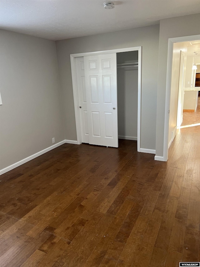 unfurnished bedroom with dark hardwood / wood-style flooring and a closet