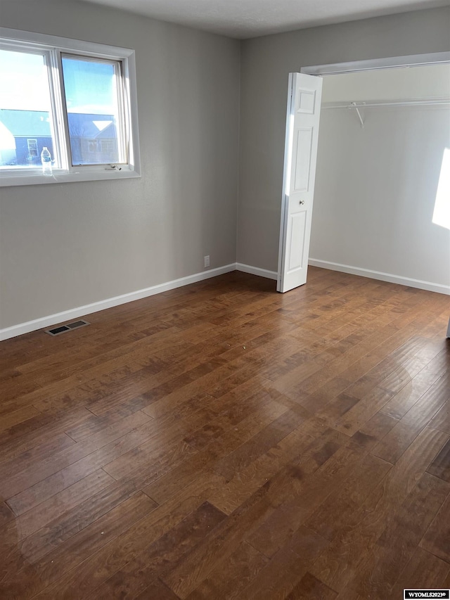 unfurnished bedroom with dark hardwood / wood-style floors and a closet