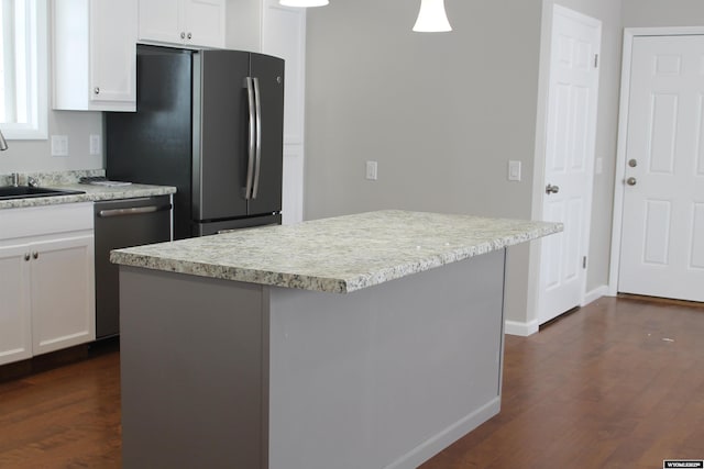 kitchen with appliances with stainless steel finishes, dark hardwood / wood-style flooring, a kitchen island, sink, and white cabinetry