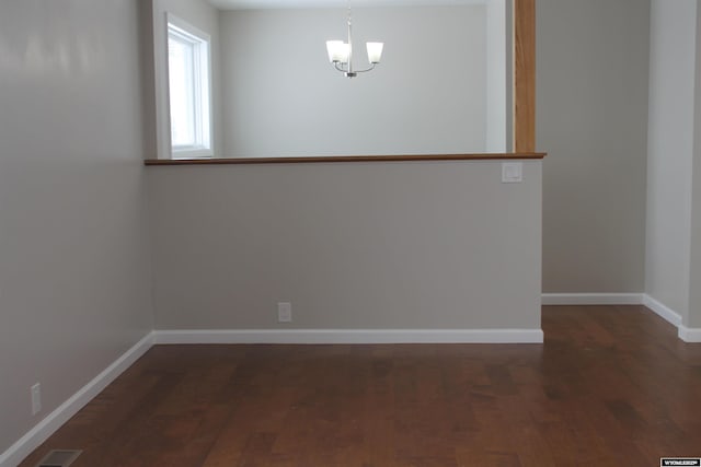 spare room featuring a notable chandelier and dark hardwood / wood-style flooring