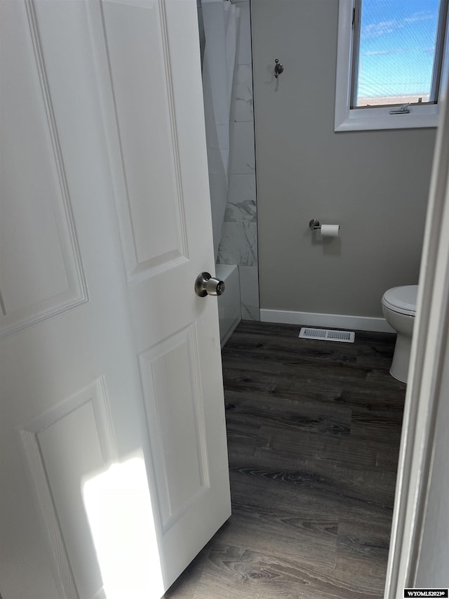 bathroom with shower / bath combination with curtain, wood-type flooring, and toilet