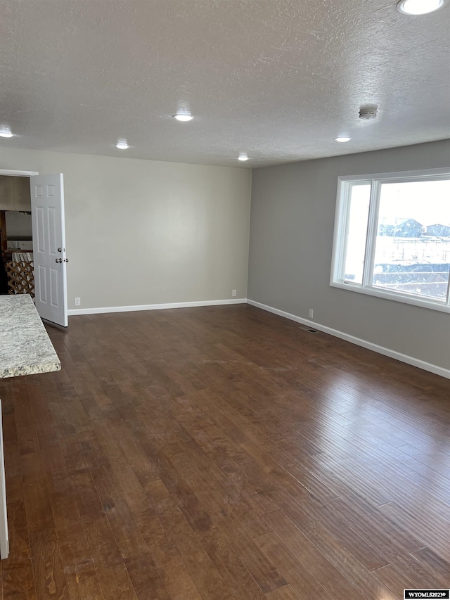 spare room with a textured ceiling and dark hardwood / wood-style floors