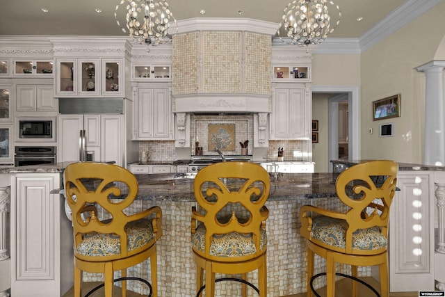 kitchen with an inviting chandelier, dark stone counters, and crown molding