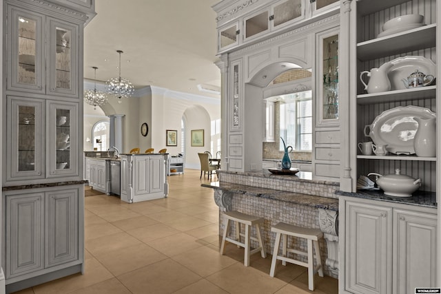 bar with sink, hanging light fixtures, light tile patterned floors, ornamental molding, and backsplash