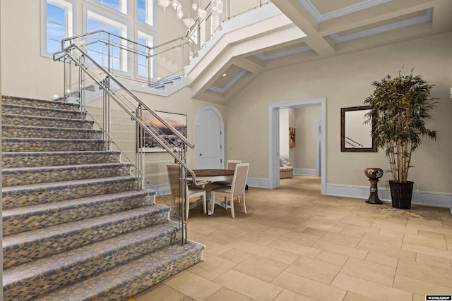 stairway with a high ceiling, ornamental molding, coffered ceiling, and beam ceiling