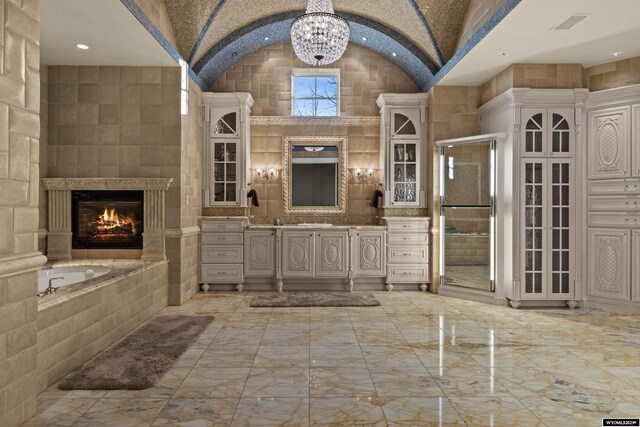 bathroom with high vaulted ceiling, brick ceiling, a tub to relax in, vanity, and an inviting chandelier