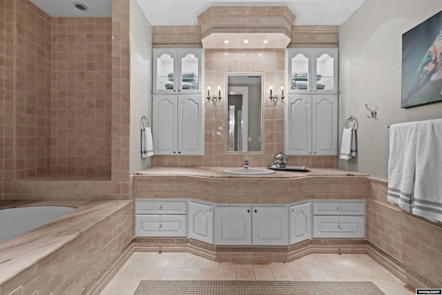 bathroom featuring tile patterned flooring, vanity, tile walls, and tiled bath