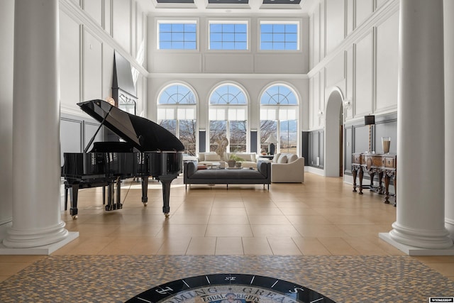 misc room with light tile patterned flooring, a towering ceiling, a mountain view, and ornate columns