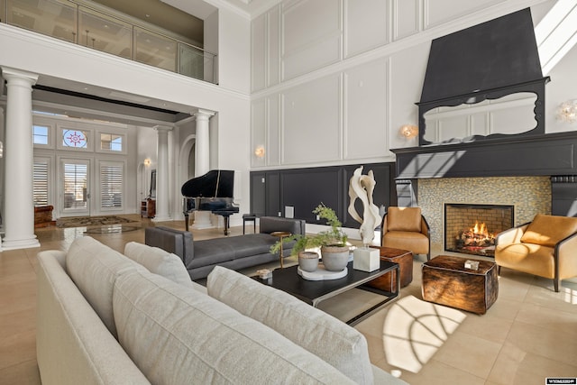 tiled living room featuring a towering ceiling, decorative columns, and a tile fireplace