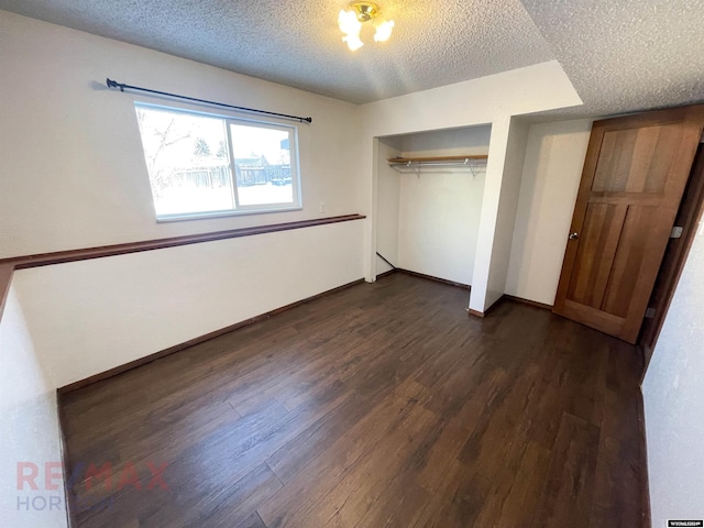 unfurnished bedroom featuring a textured ceiling, dark wood-type flooring, a closet, and baseboards