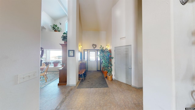 corridor featuring high vaulted ceiling and light tile patterned floors