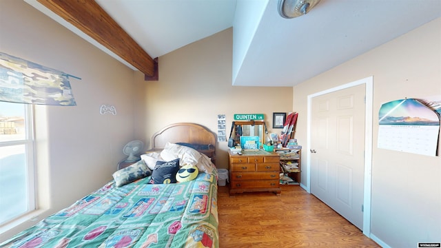 bedroom featuring lofted ceiling with beams, hardwood / wood-style flooring, and multiple windows