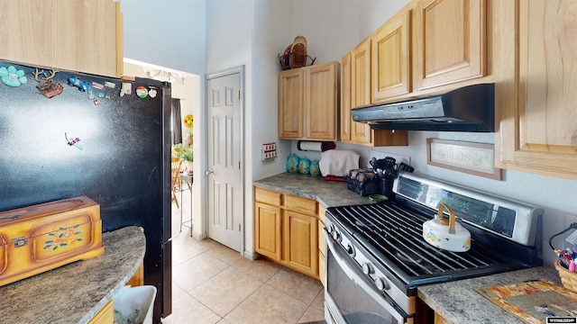 kitchen featuring light brown cabinets, black fridge, stainless steel range with gas cooktop, and light tile patterned floors