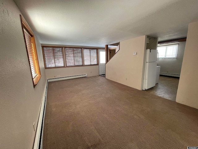 interior space with a textured ceiling and baseboard heating