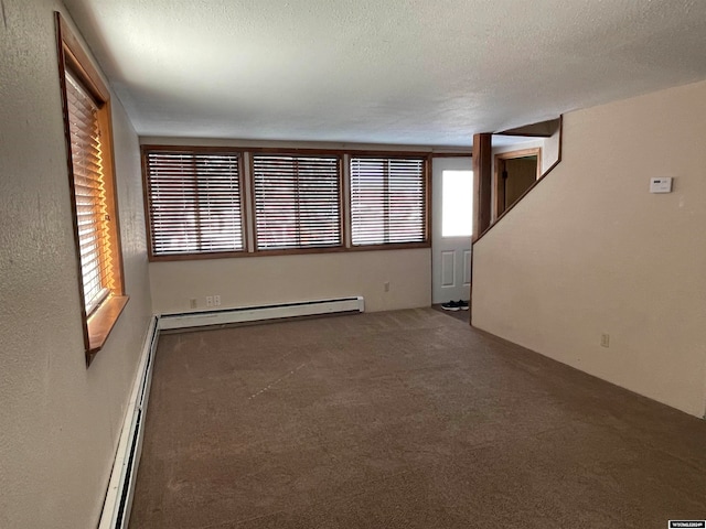 carpeted empty room featuring a textured ceiling and a baseboard heating unit