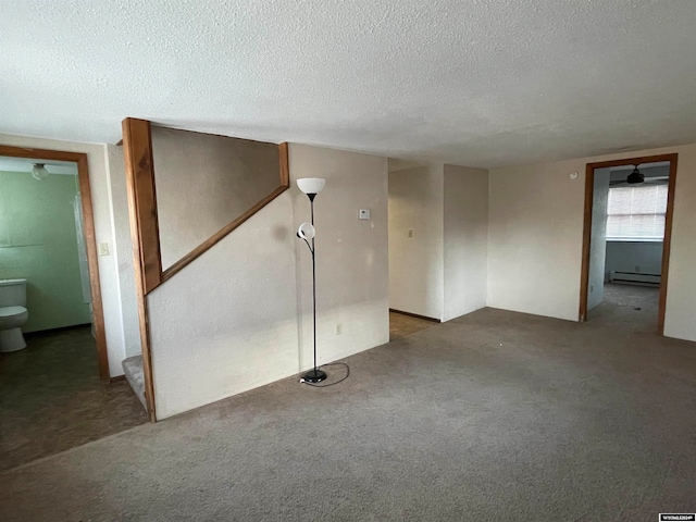 carpeted empty room featuring ceiling fan, baseboard heating, and a textured ceiling